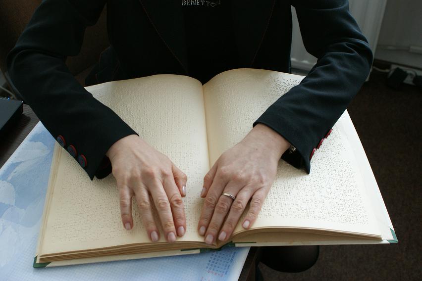 Osoba niewidoma czyta książkę w Braille'u